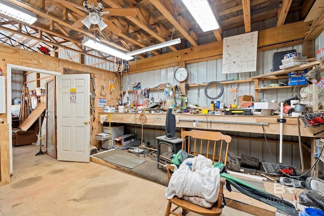 misc room with a workshop area, ceiling fan, concrete floors, and wood walls