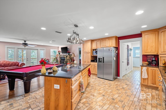 kitchen with stainless steel appliances, decorative light fixtures, a kitchen island, a stone fireplace, and pool table