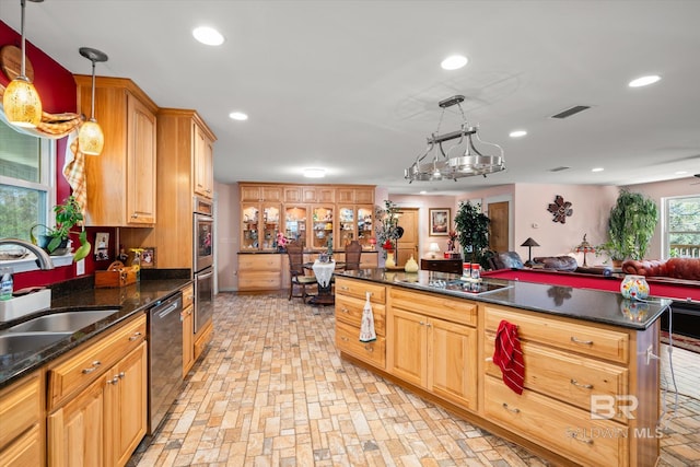 kitchen featuring stainless steel appliances, sink, a notable chandelier, dark stone countertops, and hanging light fixtures