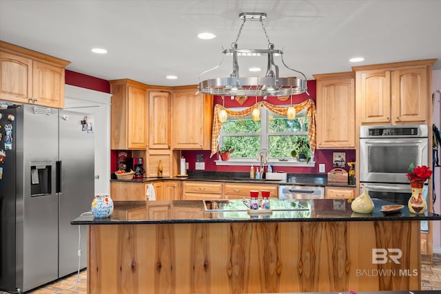 kitchen featuring appliances with stainless steel finishes, sink, a kitchen island, and dark stone countertops