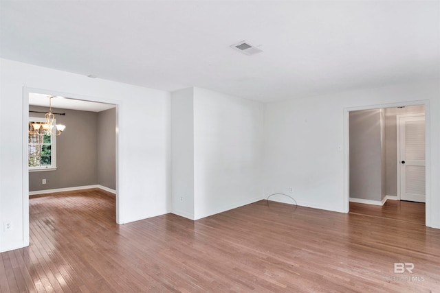 spare room with wood-type flooring and a notable chandelier