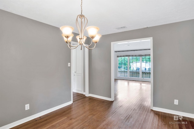 spare room featuring dark hardwood / wood-style floors and an inviting chandelier