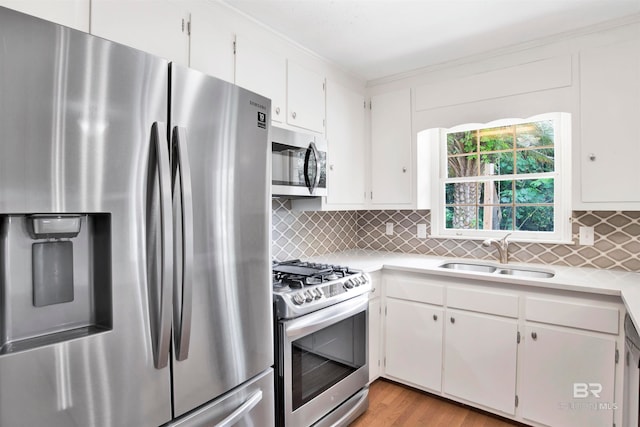 kitchen with light wood-type flooring, white cabinetry, stainless steel appliances, sink, and tasteful backsplash