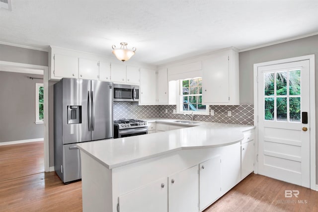 kitchen featuring plenty of natural light, light hardwood / wood-style floors, stainless steel appliances, and kitchen peninsula