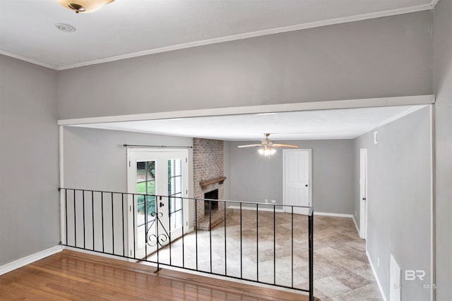 unfurnished room featuring crown molding, light hardwood / wood-style flooring, a brick fireplace, brick wall, and ceiling fan