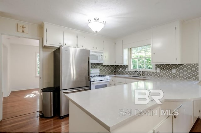 kitchen with white appliances, white cabinetry, dark hardwood / wood-style floors, sink, and tasteful backsplash