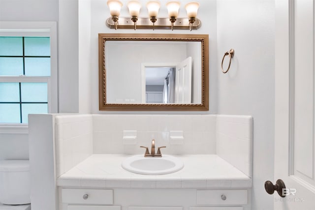 bathroom with vanity, tasteful backsplash, and toilet