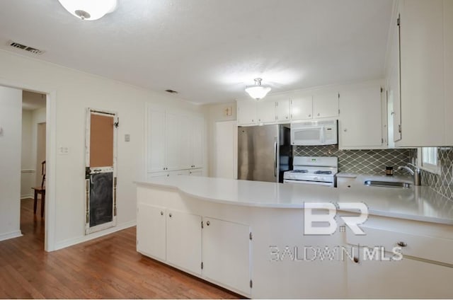 kitchen featuring white appliances, white cabinetry, hardwood / wood-style floors, backsplash, and sink