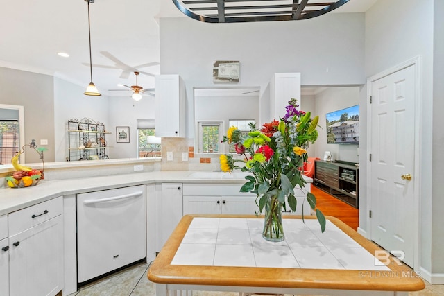 kitchen featuring light hardwood / wood-style flooring, backsplash, white dishwasher, decorative light fixtures, and white cabinets