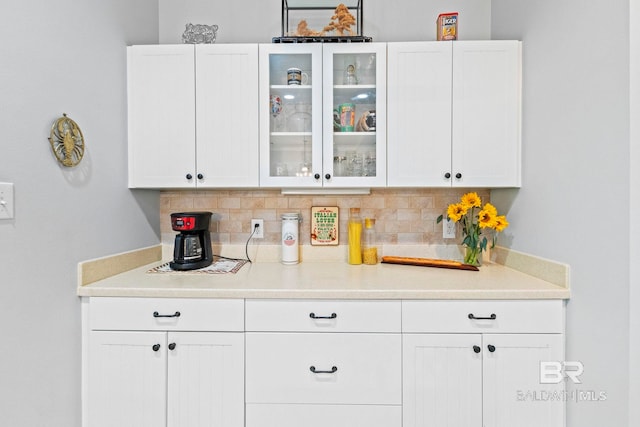 bar featuring decorative backsplash and white cabinets