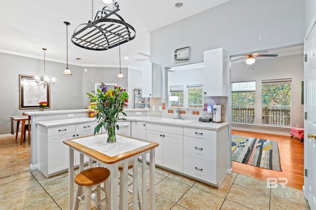 kitchen featuring sink, backsplash, hanging light fixtures, white cabinetry, and light tile patterned floors