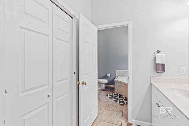 bathroom featuring vanity, tile patterned flooring, toilet, and tiled bath