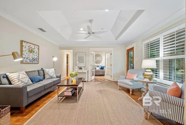 living room with hardwood / wood-style floors, ceiling fan, and a raised ceiling