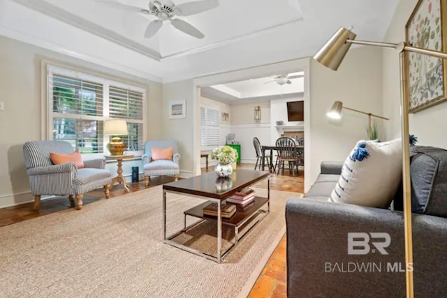 living room with a tray ceiling, ceiling fan, a fireplace, and wood-type flooring