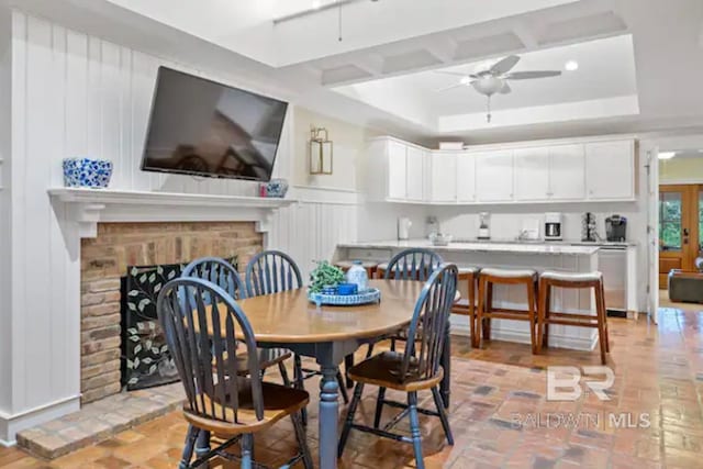 dining space with a fireplace, french doors, a tray ceiling, and ceiling fan