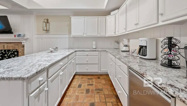 kitchen featuring a fireplace, white cabinetry, and light stone counters