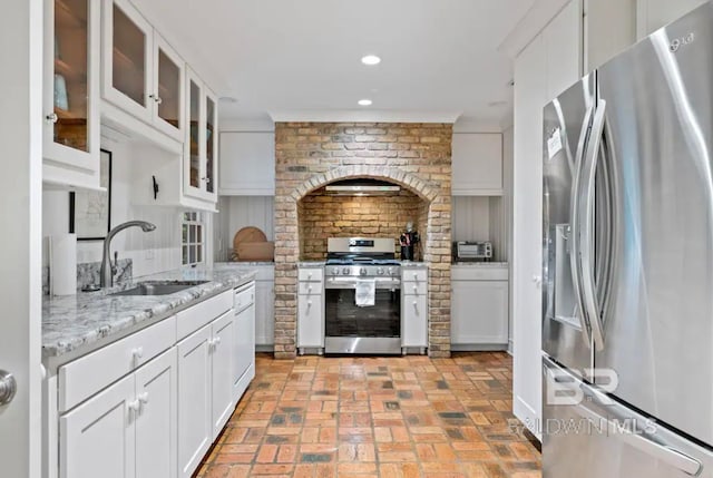 kitchen featuring light stone countertops, tasteful backsplash, stainless steel appliances, sink, and white cabinets