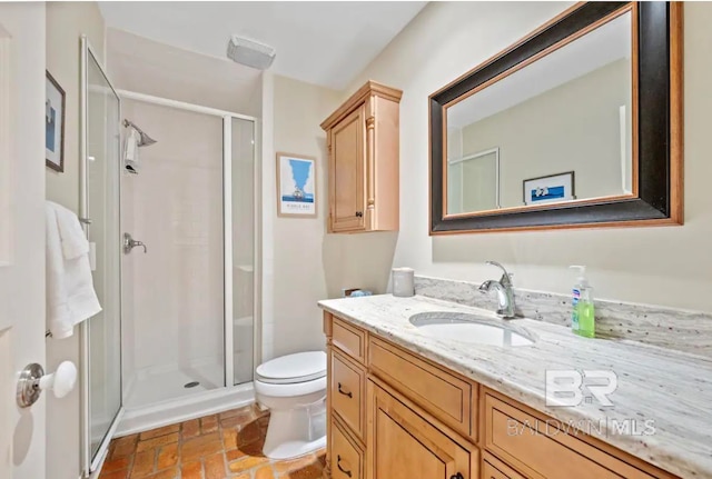 bathroom with a shower with door, vanity, and toilet