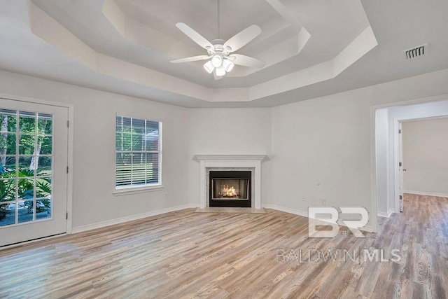 31246 Shambo Rd, Spanish Fort, AL 36527 - unfurnished living room with a tray ceiling, wood finished floors, plenty of natural light, and a ceiling fan
