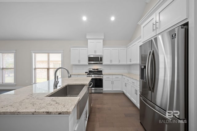 kitchen with white cabinets, light stone counters, stainless steel appliances, recessed lighting, and a center island with sink