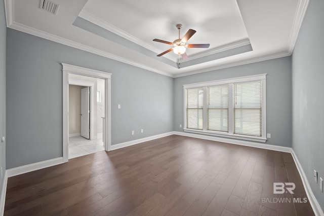 spare room with a ceiling fan, visible vents, crown molding, hardwood / wood-style flooring, and a tray ceiling