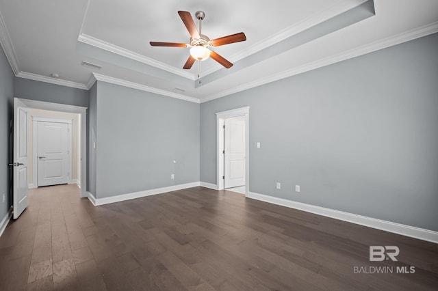empty room with crown molding, a ceiling fan, baseboards, dark wood-type flooring, and a tray ceiling