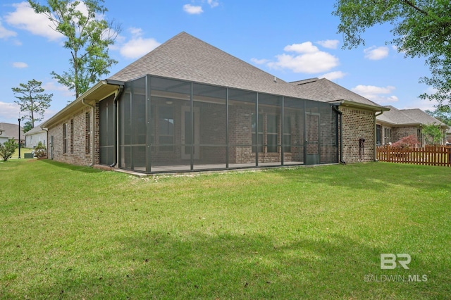back of property with a lawn, fence, a sunroom, and brick siding