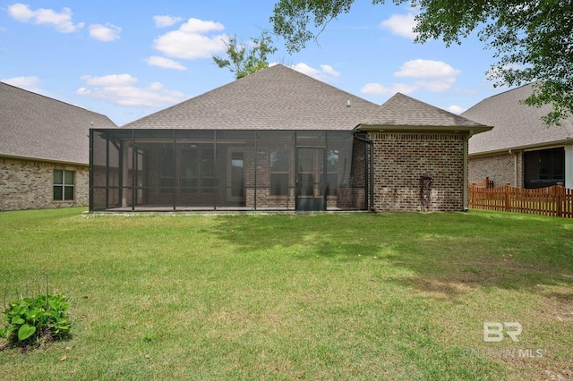 back of property with fence, a shingled roof, brick siding, a sunroom, and a lawn