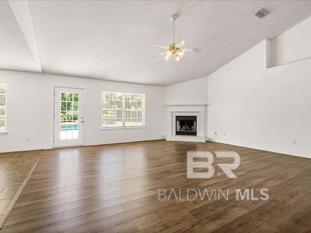 11554 Braga Dr, Daphne, AL 36526 - unfurnished living room with a textured ceiling, ceiling fan, lofted ceiling, hardwood / wood-style floors, and a fireplace