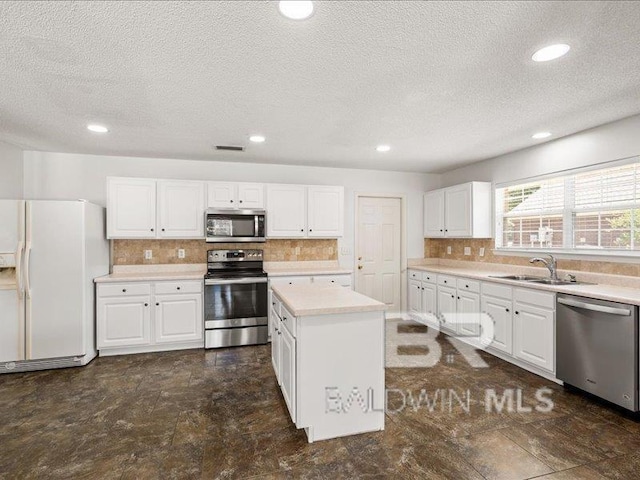 11554 Braga Dr, Daphne, AL 36526 - kitchen with appliances with stainless steel finishes, a sink, a textured ceiling, light countertops, and tasteful backsplash