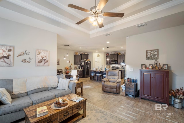 living room featuring crown molding, a raised ceiling, light hardwood / wood-style floors, and ceiling fan