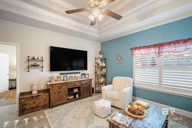 living room featuring ornamental molding, hardwood / wood-style flooring, a tray ceiling, and ceiling fan