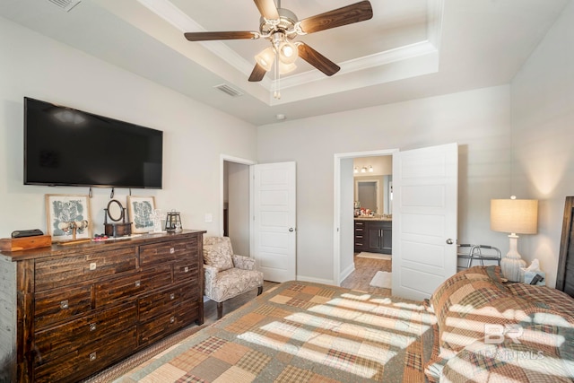 bedroom featuring a raised ceiling, ensuite bathroom, light wood-type flooring, and ceiling fan