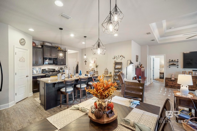 kitchen featuring a kitchen breakfast bar, black appliances, hanging light fixtures, and an island with sink