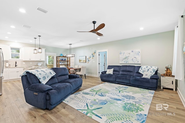 living room with ceiling fan, sink, and light wood-type flooring