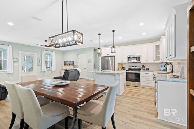 dining room with an inviting chandelier, sink, and light hardwood / wood-style flooring