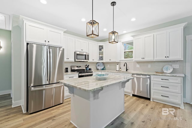 kitchen featuring white cabinetry, decorative light fixtures, a kitchen island, stainless steel appliances, and light hardwood / wood-style floors