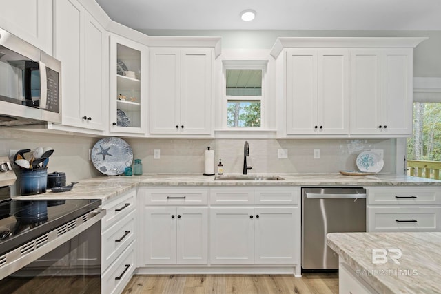 kitchen featuring sink, appliances with stainless steel finishes, white cabinetry, tasteful backsplash, and light stone countertops