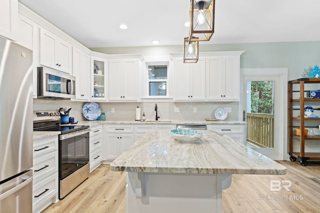 kitchen with appliances with stainless steel finishes, a breakfast bar, sink, and hanging light fixtures