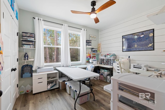 office with wood-type flooring, ceiling fan, and wood walls