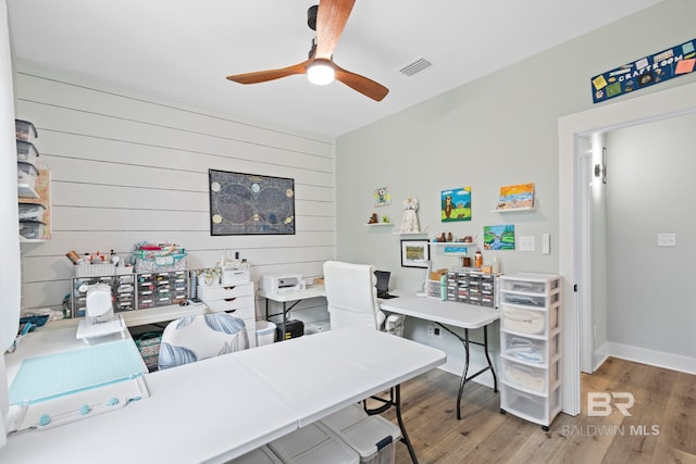 office area featuring wood-type flooring, ceiling fan, and wood walls