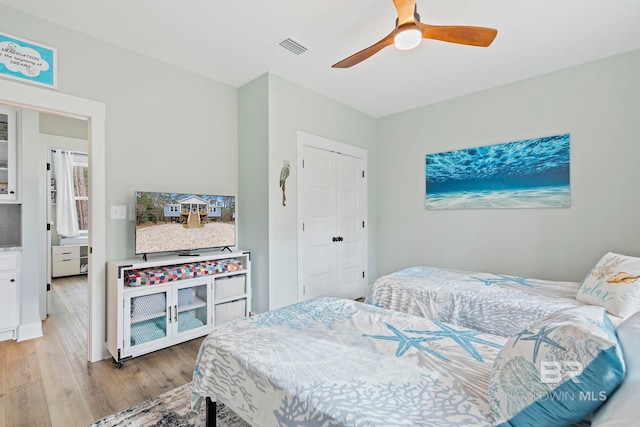 bedroom with light hardwood / wood-style floors, ceiling fan, and a closet