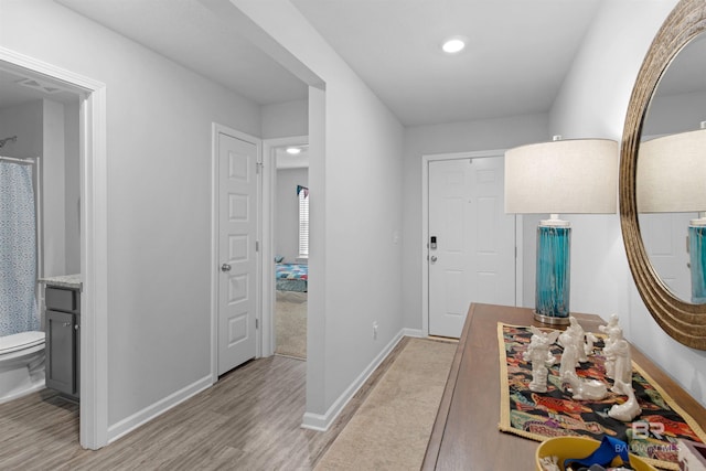 hallway with recessed lighting, light wood-type flooring, and baseboards