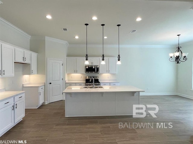 kitchen featuring appliances with stainless steel finishes, wood finish floors, visible vents, and a center island with sink