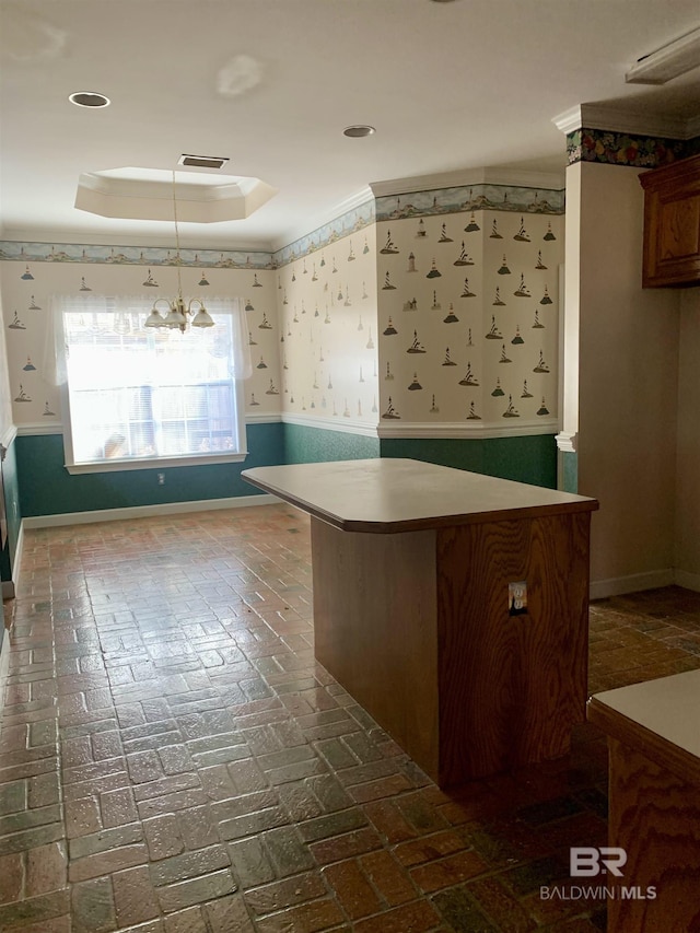 kitchen featuring a tray ceiling, decorative light fixtures, a chandelier, and a kitchen bar