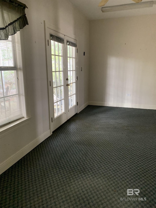 empty room featuring french doors, a healthy amount of sunlight, and dark colored carpet