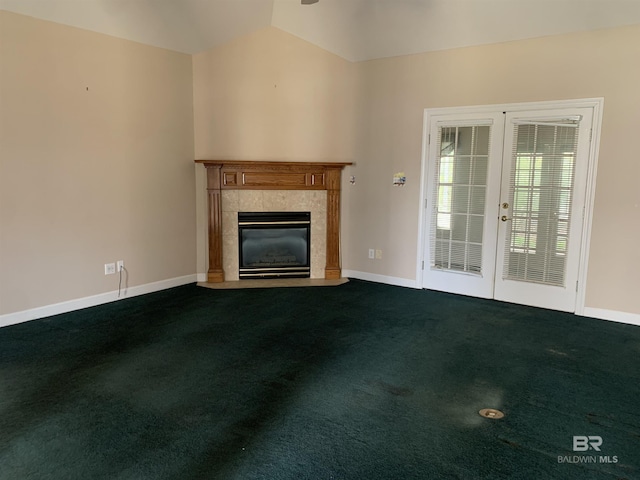 unfurnished living room featuring a tiled fireplace, lofted ceiling, carpet flooring, and french doors