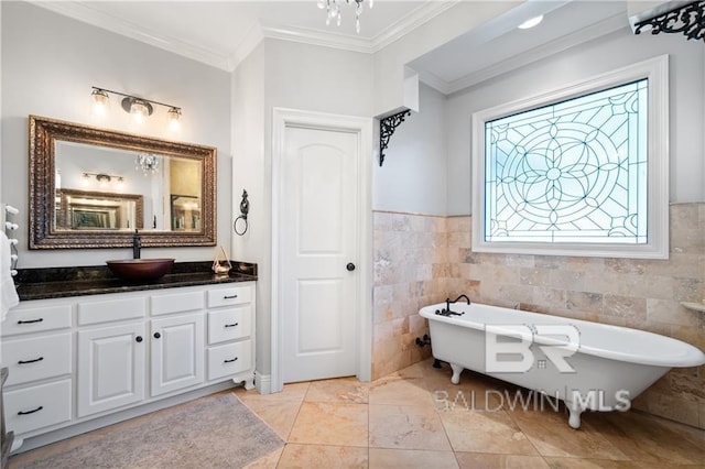 bathroom with a tub, vanity, tile walls, and ornamental molding