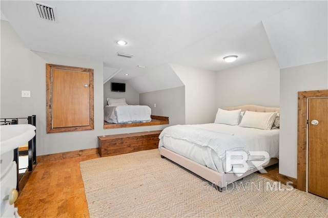 bedroom with light wood-type flooring and vaulted ceiling