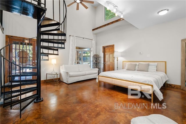 bedroom with concrete flooring, ceiling fan, and a high ceiling